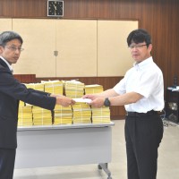 川又労働基準部長に、最賃行政に関する要請書を手渡す、連合福島最低賃金対策委員会 生亀委員長。後ろにあるのは県内から寄せられた署名用紙